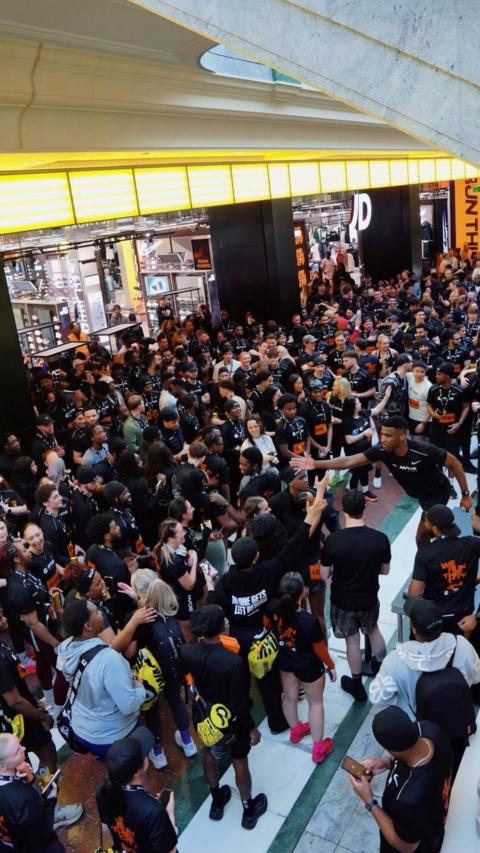 A huge crowd of people outside a JD sports store, all wearing fitness clothing