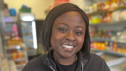 Gina Bonsu wearing a black jacket, smiling at the camera