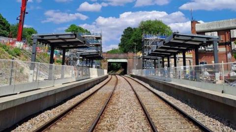 A railway track with platforms on both sides and the framework for coverings over both platforms