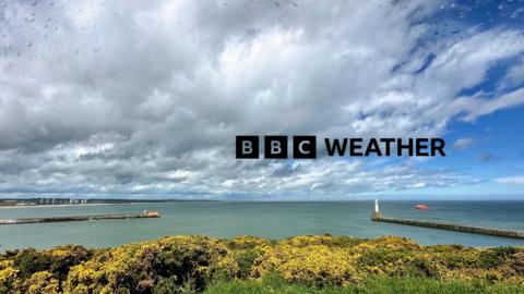The BBC Weather wordmark overlaid on a scene taken from Torry in Aberdeenshire. The vista looks north, encompassing a large swathe of the North Sea, at the entrance to Aberdeen harbour. The sky shows a mix of sunny spells and rain clouds.