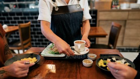 Anonymous cafe worker delivers coffee to customers