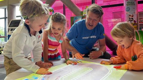 Children with John Ramsay playing on the interactive storytelling projector