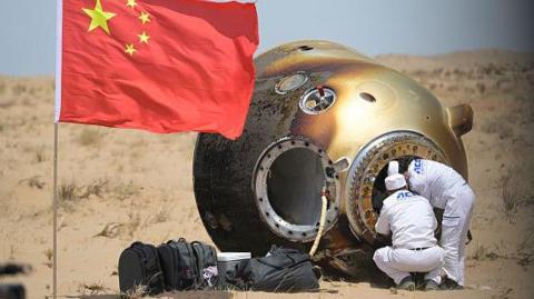 Ground crew carry crew member of the Shenzhou-19 mission out of return capsule