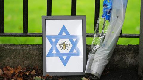 A bunch of flowers and a framed star of David with a bee in the centre, which were left at the scene in tribute after the Manchester synagogue attack