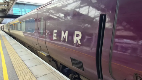 a burgundy East Midlands Railway train with the initials EMR on the side 