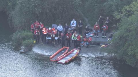 Search and rescue teams at the side of a pond