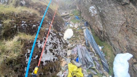 A climber shows rubbish along a path