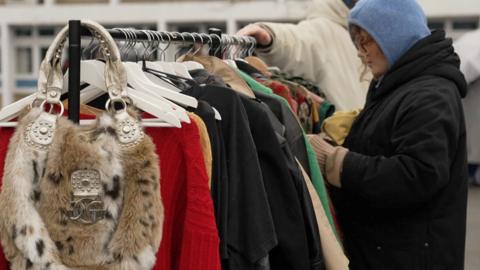 Woman looks through clothes at Peckham Car Boot sale