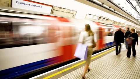 Woman walking along train platform as train drives past