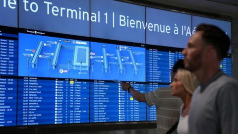 Passengers check the board displaying delayed flight information at Toronto Pearson Airport Canada 