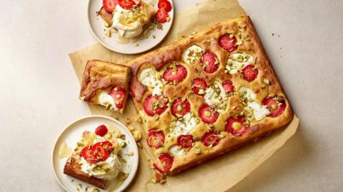 A strawberry and pistachio bake with slices on two white plates