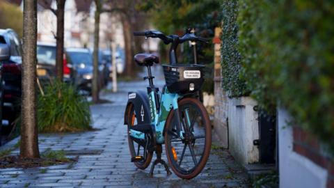 An e-bike bike in a leafy street.