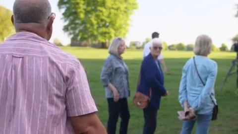 A man wearing a pink shirt has a confrontation with three women in a park.