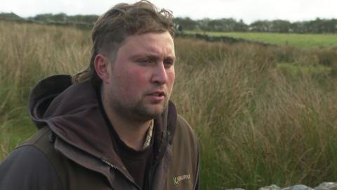 Man wearing brown hooded coat stood in field