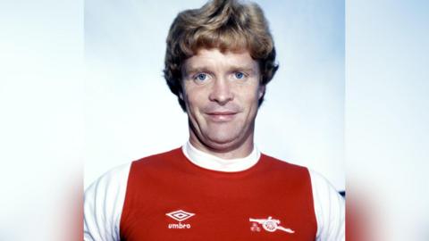 Willie Young in a red and white Arsenal shirt.