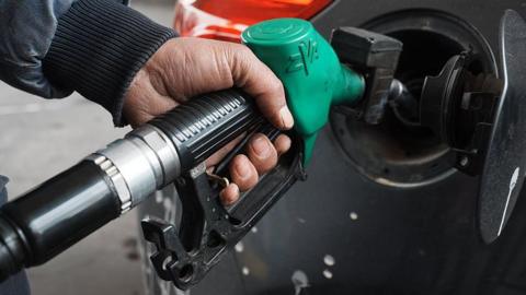 A man topping up his car's fuel using a green petrol pump