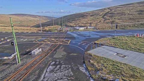A CCTV view of the mountain road. It is surrounded by hills.
