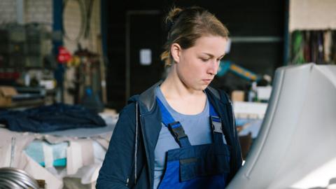 Young woman working on a machine in an industrial setting
