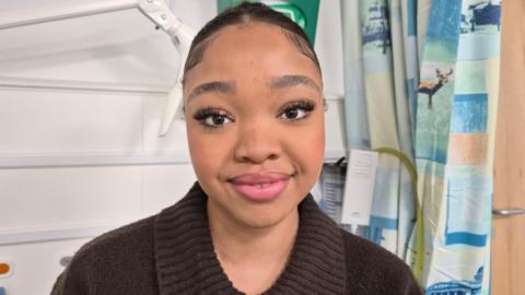A picture of a young woman smiling at the camera while sitting in a hospital room