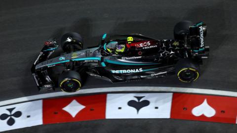 Mercedes' Lewis Hamilton drives around a corner in Las Vegas Grand Prix first practice that has the markings of card suits on the surface