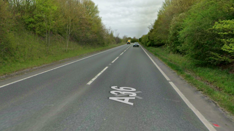 Picture of the A36. Not many cars on the road and the carriage way is surrounded by hedges and trees.