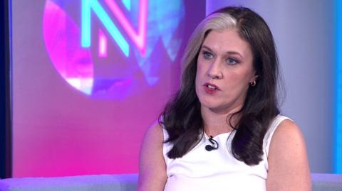 Nathalie Fleet MP sat in a TV studio wearing a white top