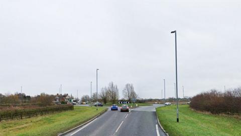 Google Street View showing the approach to the Partney roundabout on the A158. Two cars are in the left-hand lanes just about to drive on to the roundabout