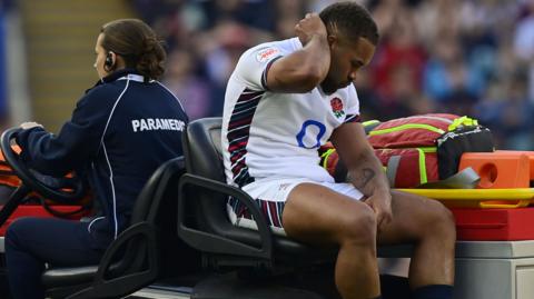 Ollie Lawrence sat on the medical car being taken off the pitch during England's game against Italy