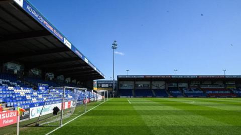 Stands and the pitch at Dingwall's stadium on a sunny day.