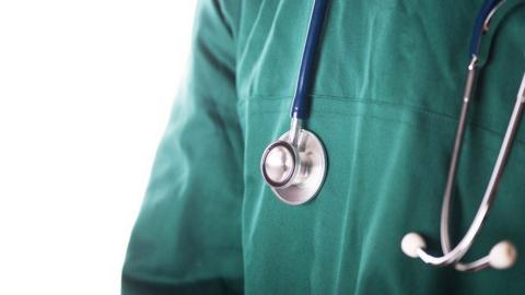 A stock image zoomed in on someone wearing mint green scrubs with a stethoscope round their neck