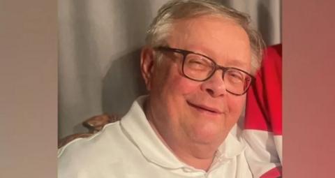 A family-issued photograph of Stuart Everett. He has grey hair and is wearing dark glasses in the photograph. Smiling, he is wearing a white polo shirt.