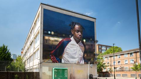 A mural of a young man in Brixton at night