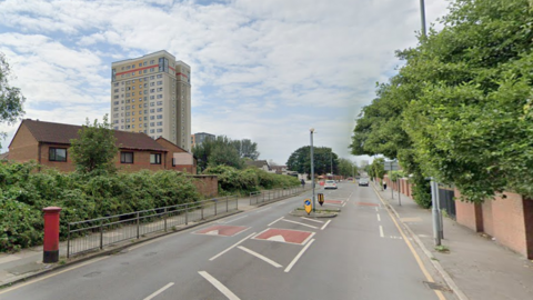 A post box on the right in Marsh Lane with traffic calming measures in the tree-lined street