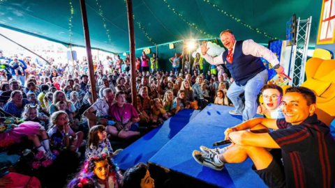 Crowds of adults and children gather in a tent at the festival to see Mr Tumble appear