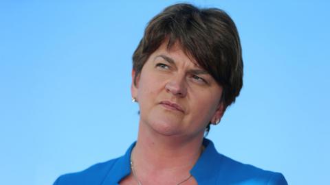 Baroness Foster, pictured from the shoulders up. She has short brown hair and is wearing a blue jacket. The background of the image is light blue. 