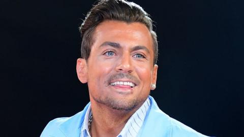 Paul Danan smiling in a turquoise suit