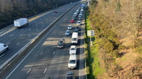 A closed motorway carriageway. Traffic is queuing on the right hand side to leave the road.