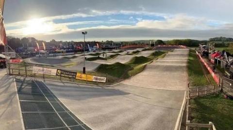 A BMX facility viewed from the sloped start of the course, looking out over undulating humps and bumps