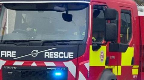 A red, white and fluorescent yellow fire engine with a blue light and 'fire rescue' written across the front. 