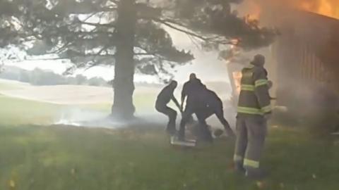 First responders perform a rescue operation in a house on fire