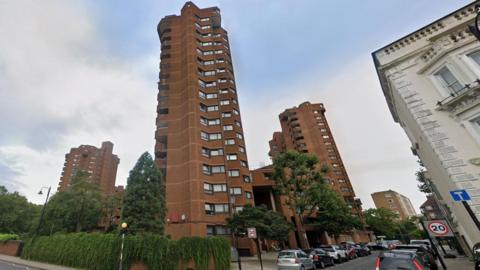 A collection of brown high-rise buildings, with trees in front.