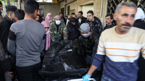 A man transports a body at a hospital in Damascus, after rebels said they had found around 40 showing signs of torture at Harasta hospital (10 December 2024)