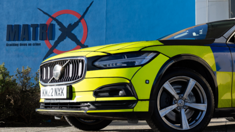 Police car in the foreground with Matrix logo on a wall behind