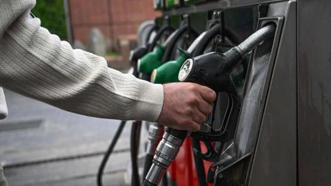 A man grabs a black fuel pump at a petrol station