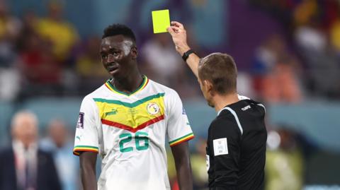 Idrissa Gueye is shown a yellow card by a referee