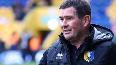 Mansfield Town boss Nigel Clough stands in a club tracksuit