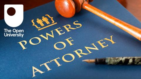 'Powers of attorney' written in gold on a bue book, with a pen and a gavel