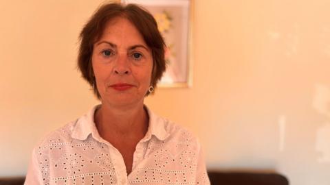 A woman with brown hair and a white shirt