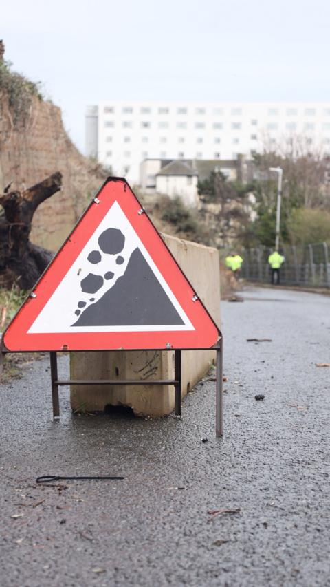 A sign warning of crumbling rocks.