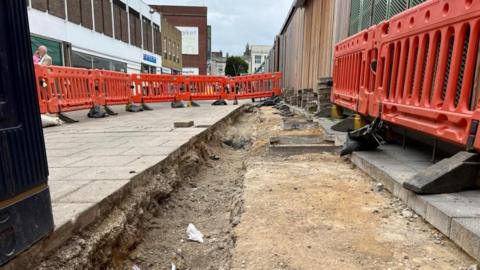 Excavation cordoned off with orange barriers near Great Yarmouth Market